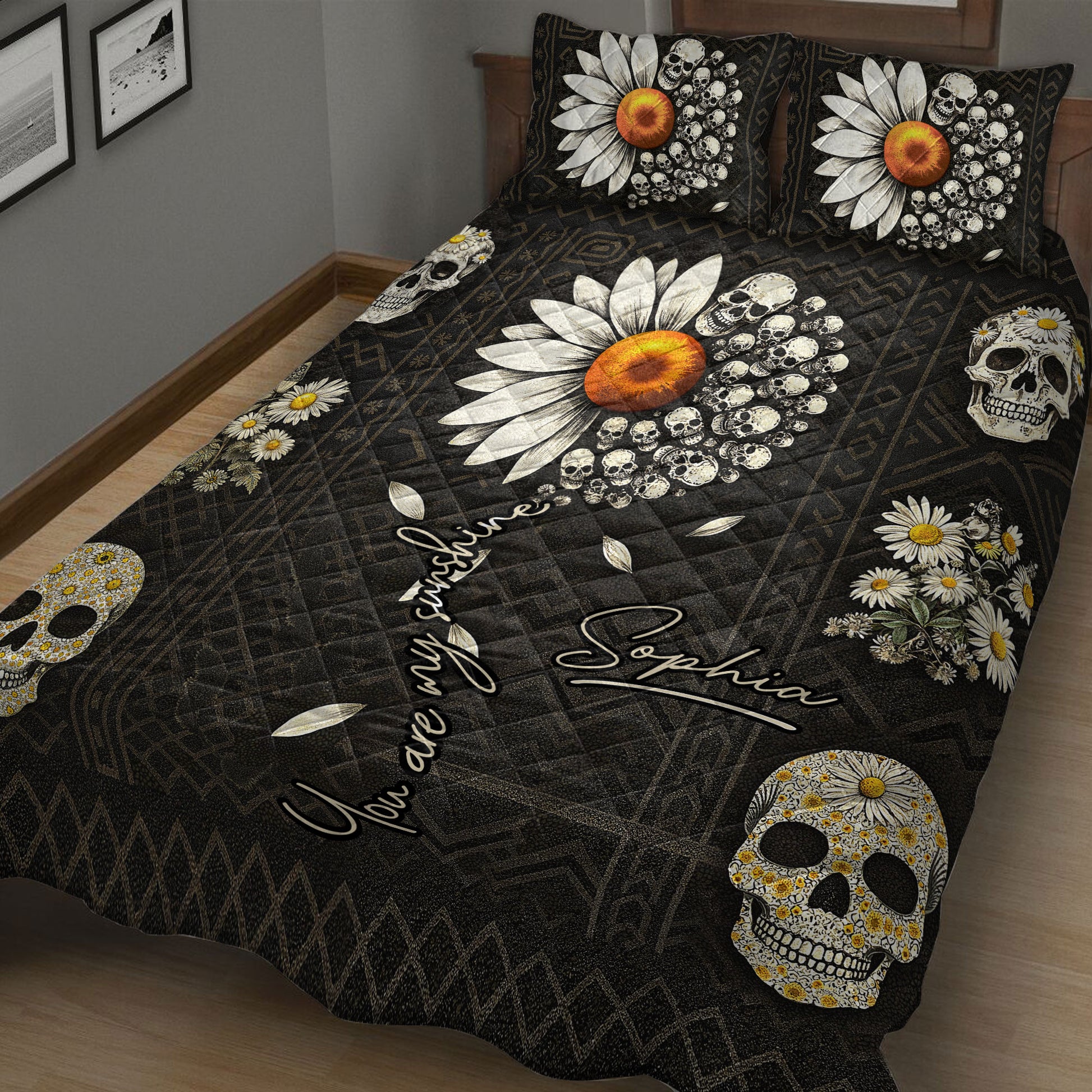 Close bedroom view of a black skull quilt blanket with daisies, orange flowers, and repeating skull artwork