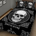 Angled bedroom view of a black skull quilt blanket with a large central skull medallion