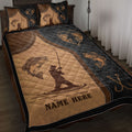 Fishing quilt blanket displayed on a bed with angler silhouettes, fish artwork, hooks, and brown and black colors