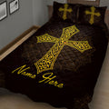 Close bedroom view of a black quilt blanket with large ornate gold cross artwork