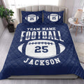 Navy football quilt blanket styled on a bedroom bed with bold football artwork
