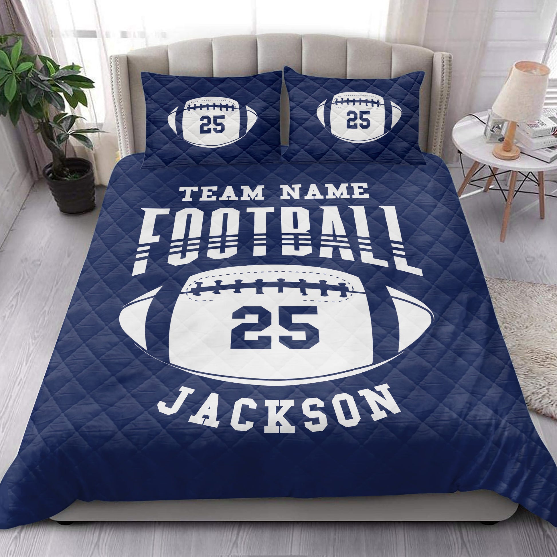 Navy football quilt blanket styled on a bedroom bed with bold football artwork