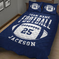 Close bedroom view of navy football quilt blanket with large white football graphic