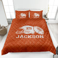 Orange football quilt blanket styled on a bedroom bed with helmet and football graphics