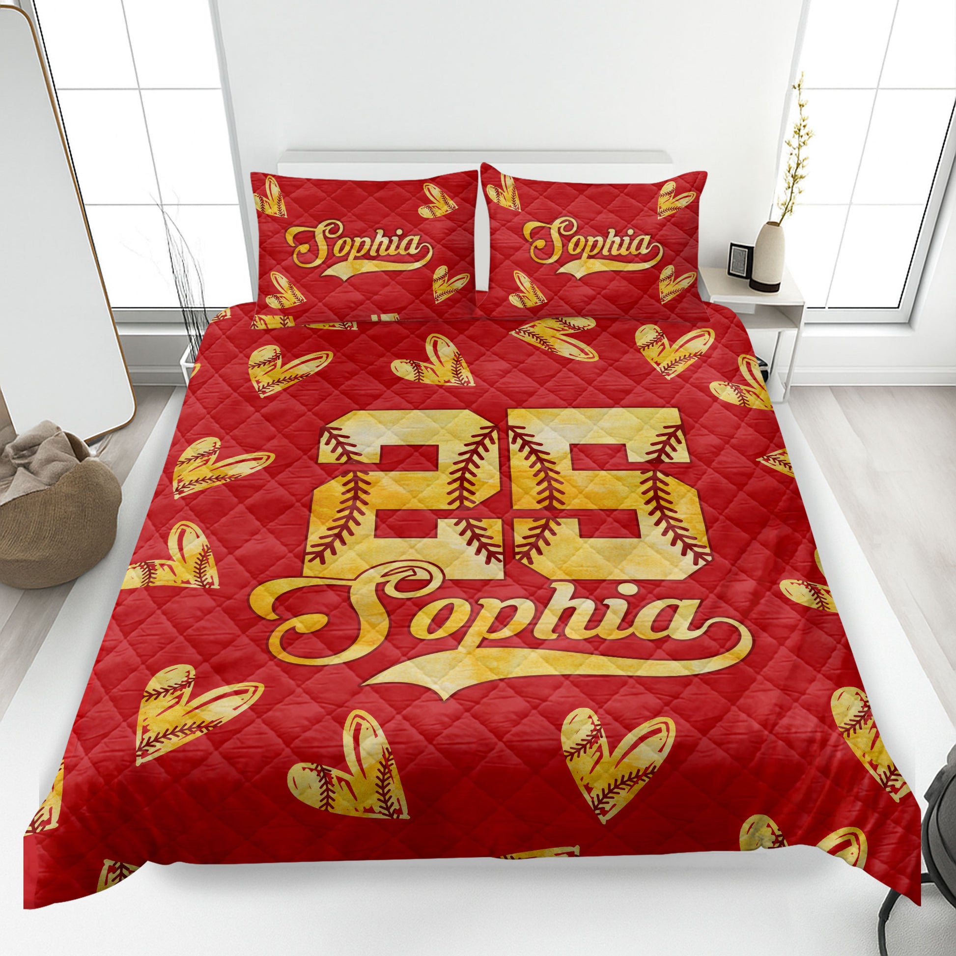 Red softball quilt blanket on a bedroom bed with golden stitched softball hearts and bold athletic design