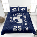 Navy soccer quilt blanket styled on a bedroom bed with large soccer ball artwork