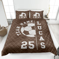 Brown soccer quilt blanket on a bedroom bed featuring bold white soccer ball graphics