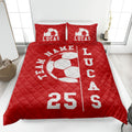 Red soccer quilt blanket styled on a bed with large white soccer ball artwork