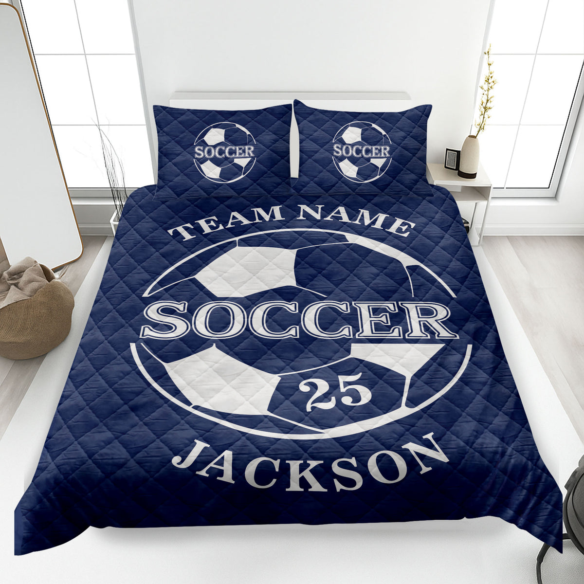Navy soccer quilt blanket shown on a bed with bold soccer ball graphics and white sports lettering