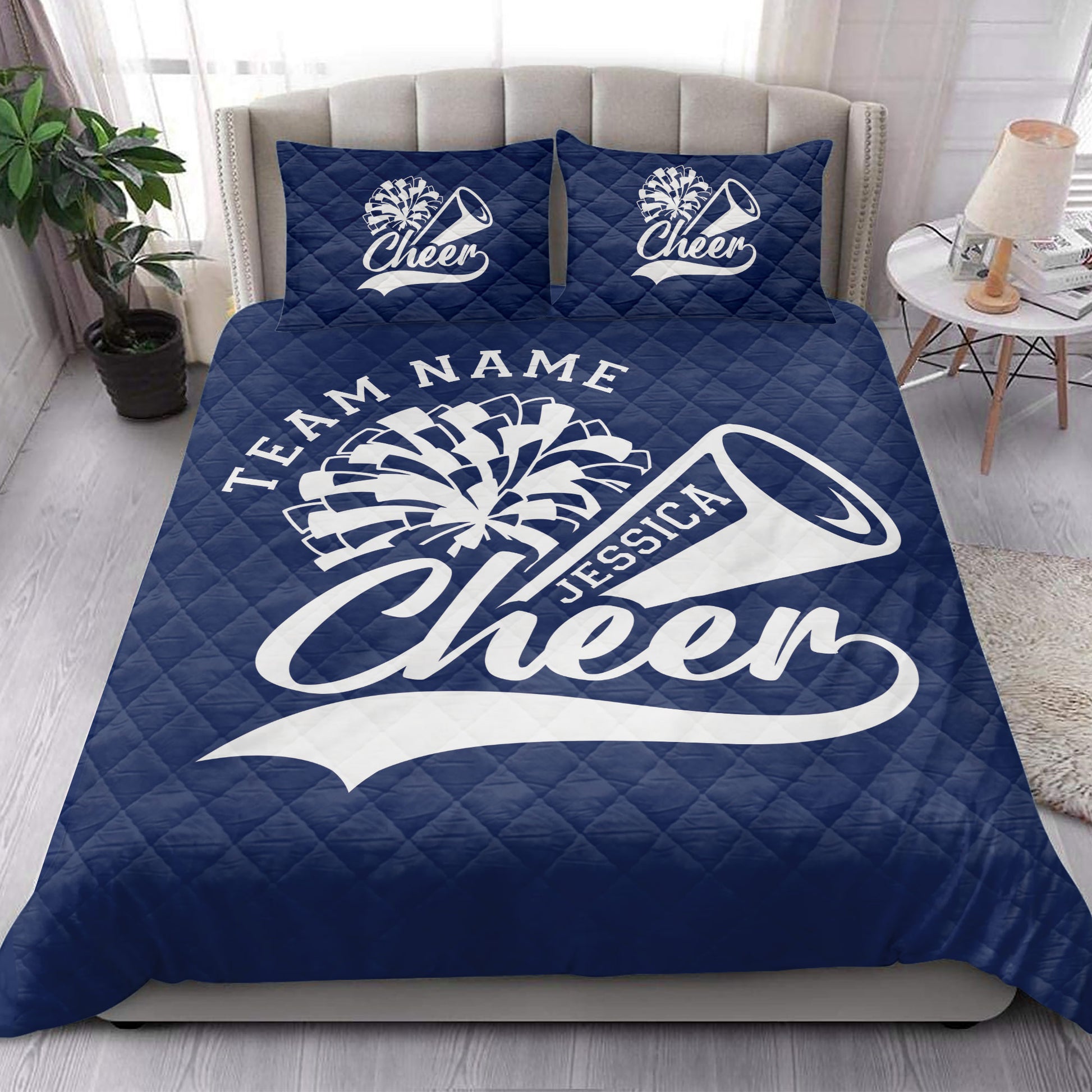 Navy cheerleading quilt blanket styled in a bright bedroom with matching cheer-themed pillows