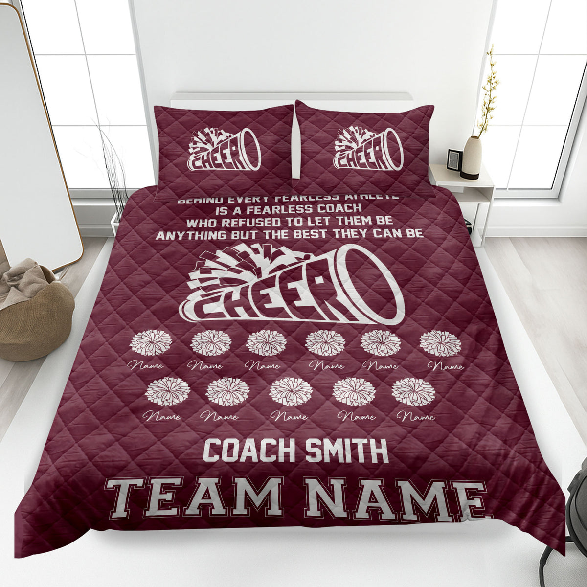 Maroon cheerleading quilt blanket featuring white megaphone and pom-pom artwork on a bed