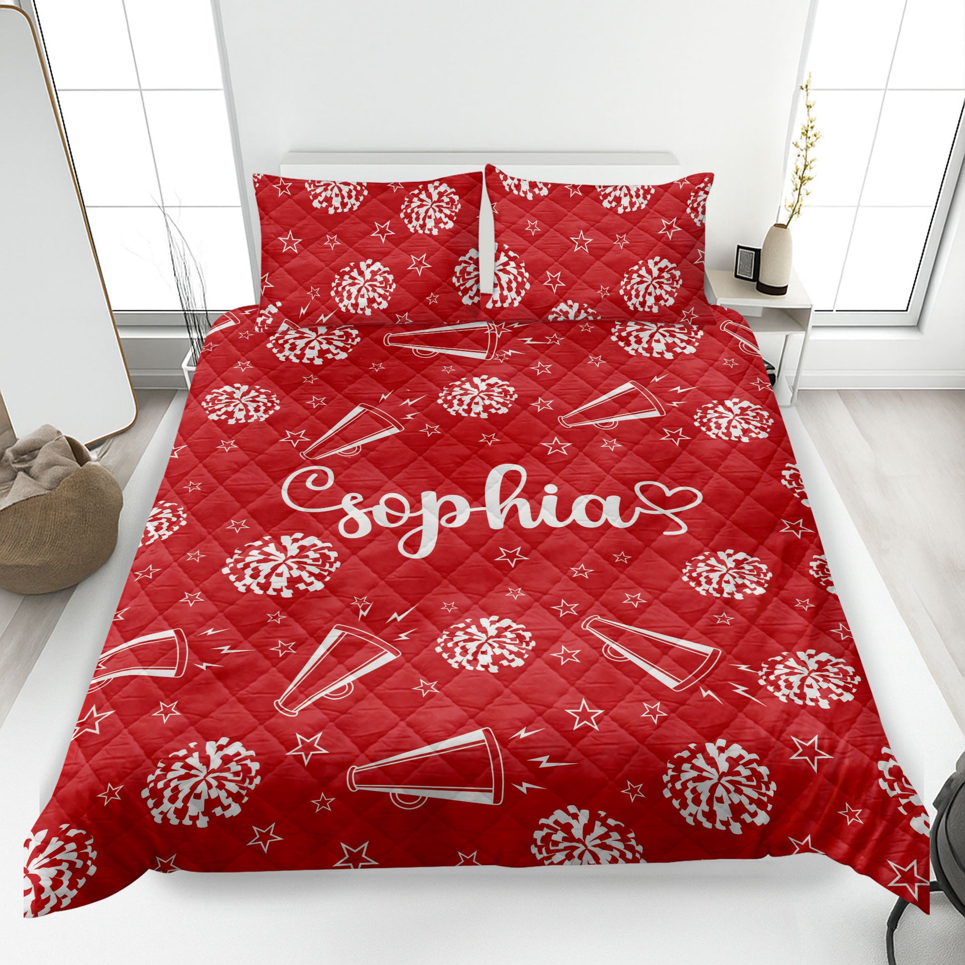 Red cheerleading quilt blanket styled on a bed with pom-poms, megaphones, stars, and lightning motifs