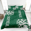 Green cheerleading quilt blanket styled on a bedroom bed with bold pom-pom graphics