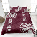 Maroon cheerleading quilt blanket displayed on a bed with white pom-pom artwork