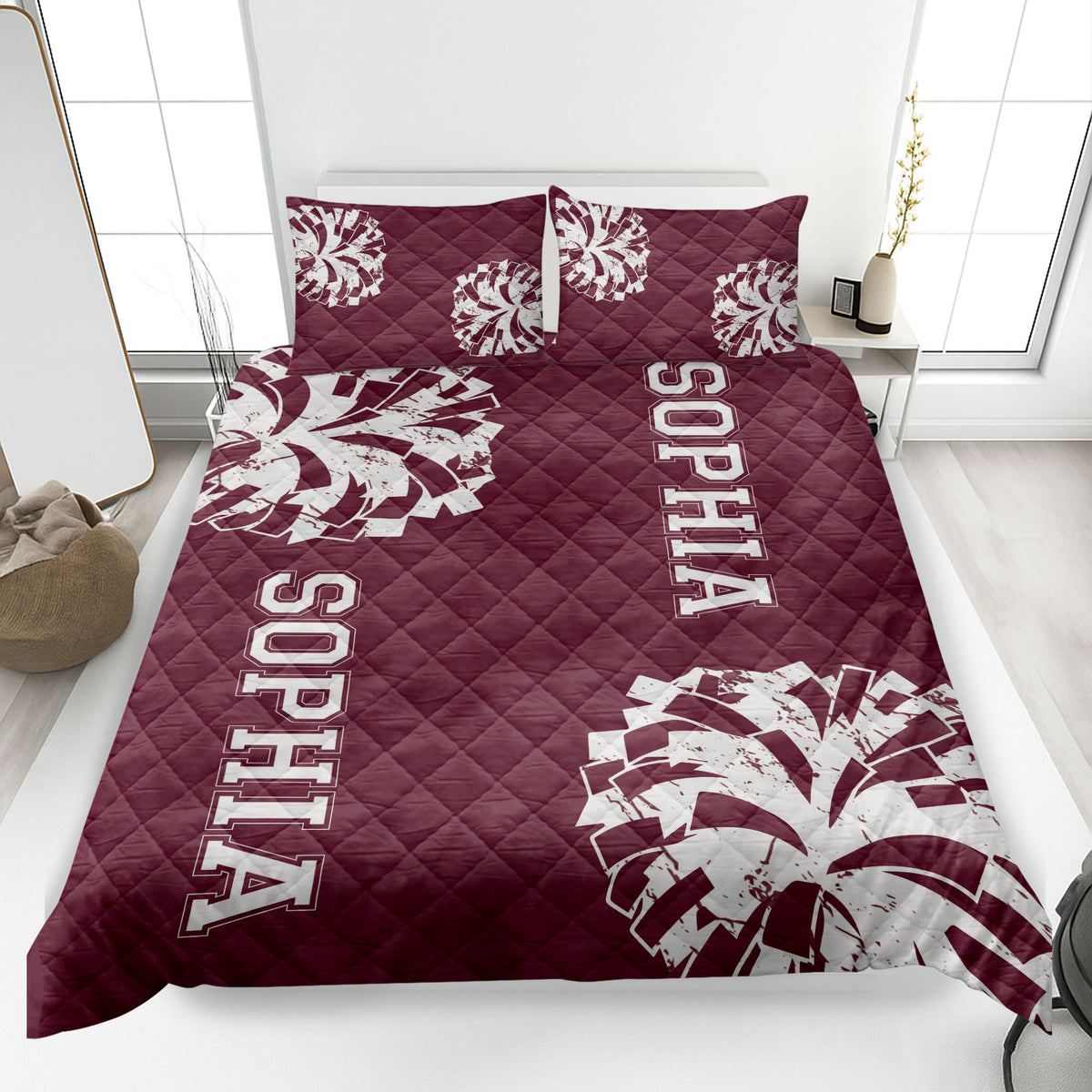 Maroon cheerleading quilt blanket displayed on a bed with white pom-pom artwork