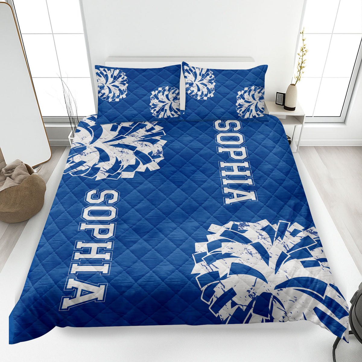 Blue cheerleading quilt blanket displayed on a bed with energetic pom-pom graphics