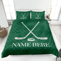 Green hockey quilt blanket on a bed featuring crossed hockey sticks and puck artwork