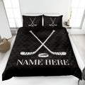 Black hockey quilt blanket displayed on a bed with bold white crossed sticks and puck design