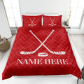 Red hockey quilt blanket on a bed featuring white crossed hockey sticks and puck artwork