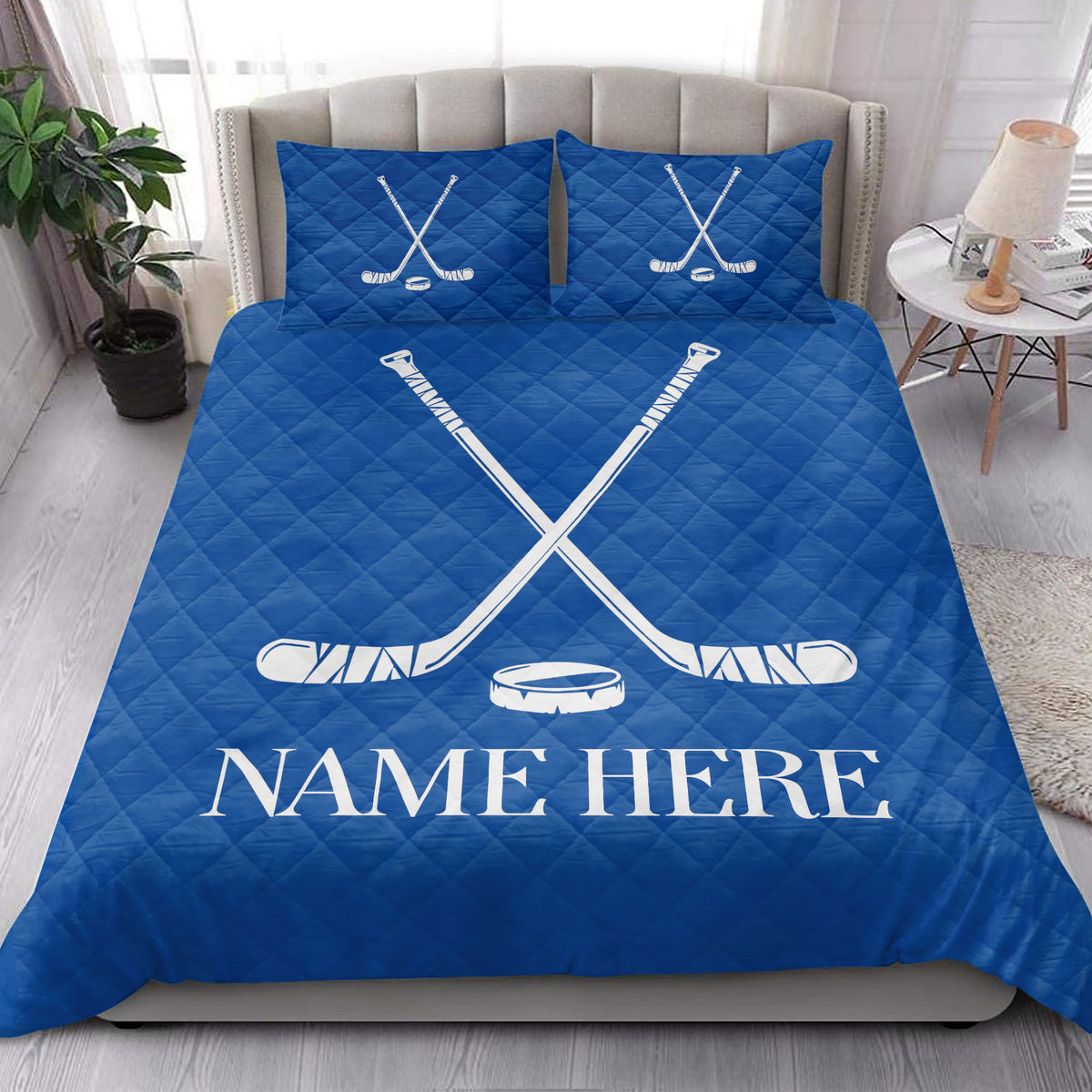 Blue hockey quilt blanket presented in a bright bedroom with crossed sticks and puck design