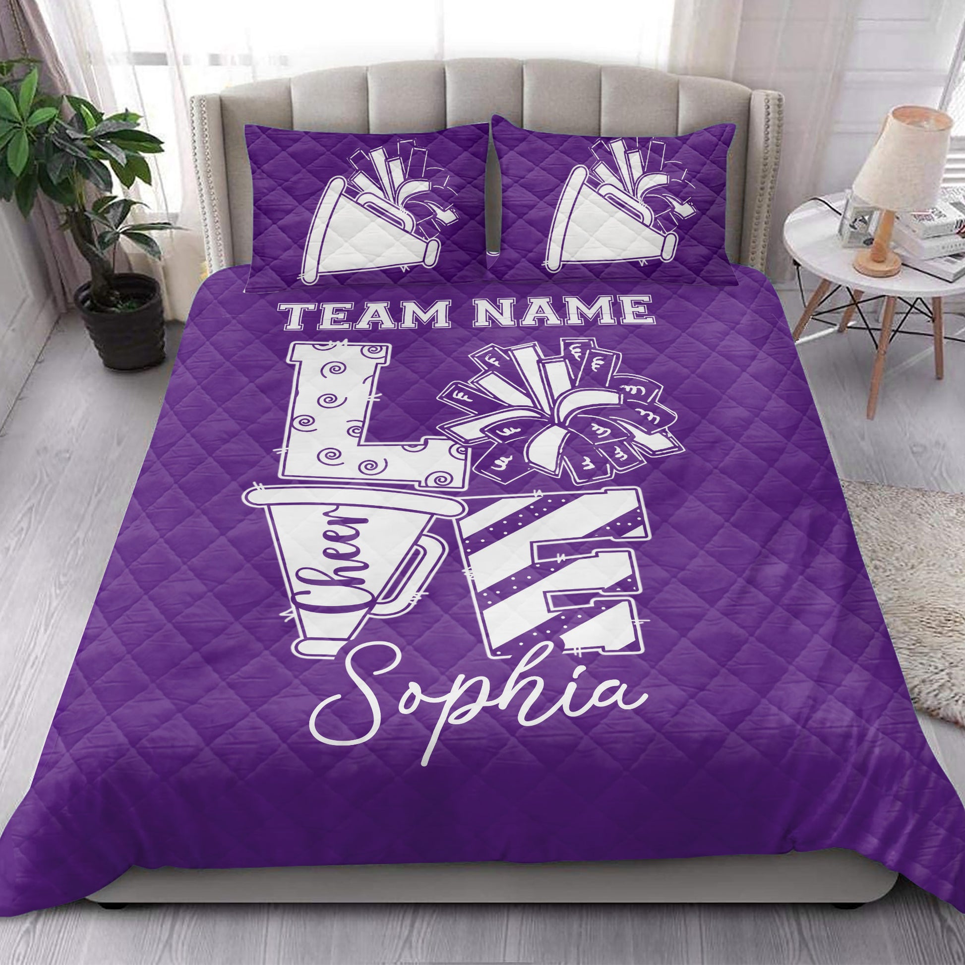 Purple cheerleading quilt blanket styled in a bedroom with megaphone, pom pom, and bow graphics