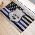 Police-themed entryway rug positioned beside a doorway with a badge and blue stripe flag design