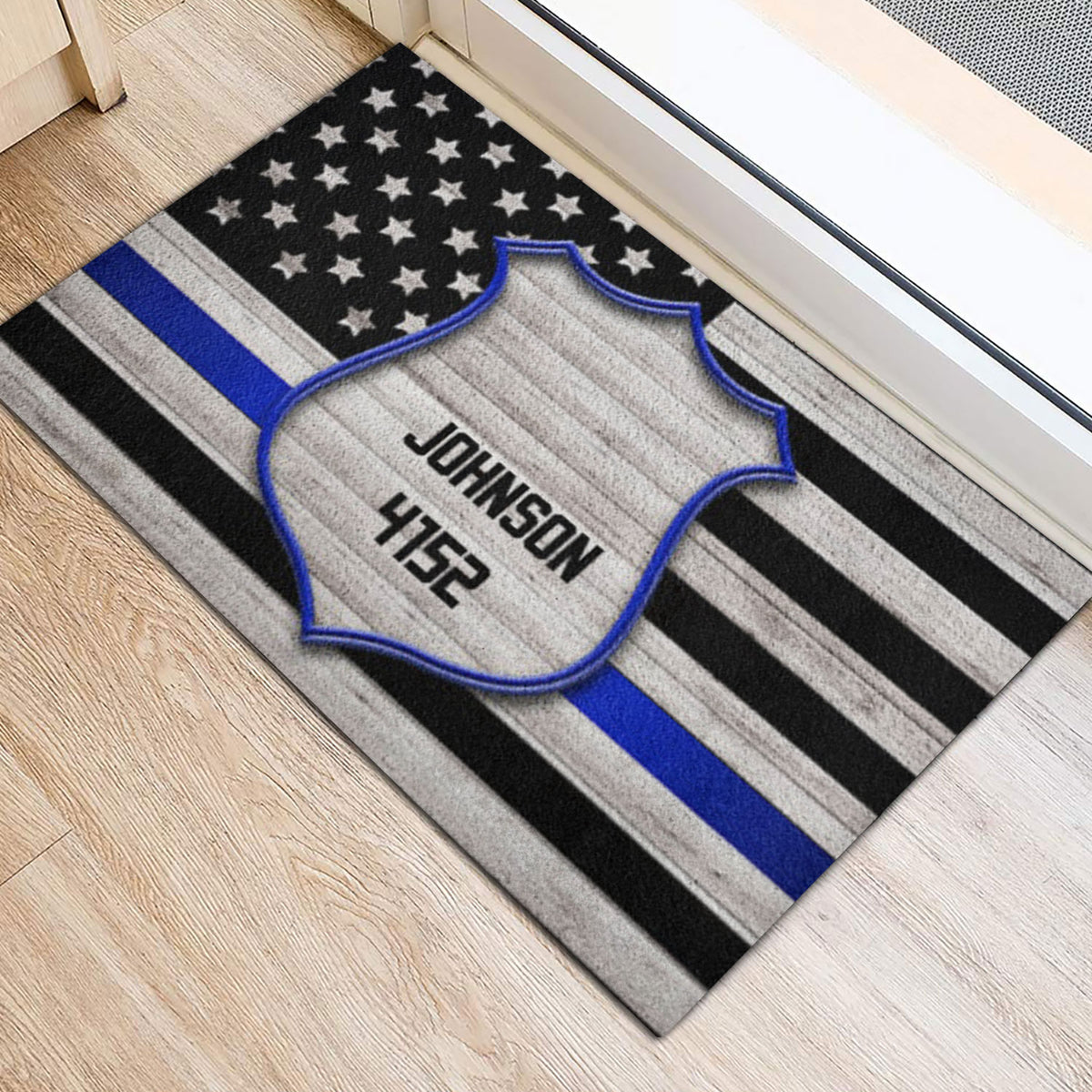 Police-themed entryway rug positioned beside a doorway with a badge and blue stripe flag design