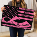 Person holding a black and pink breast cancer ribbon doormat with a solidarity message