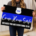 Person holding a black police doormat featuring a white badge and blue stripe artwork