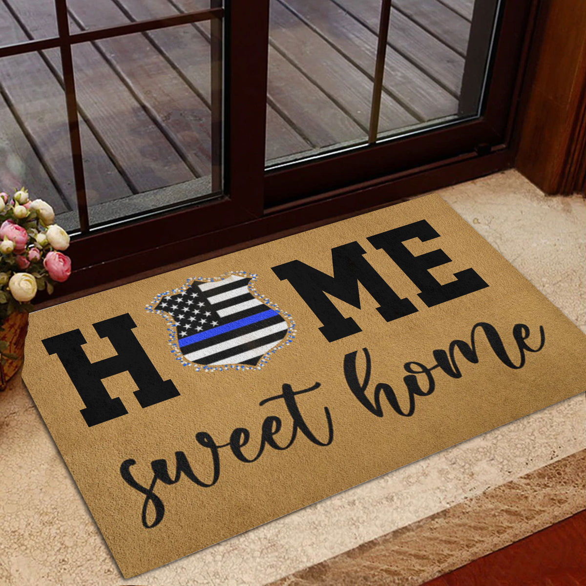 Police-themed welcome door mat styled beside a glass entry door with flowers