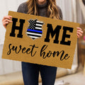 Person holding a tan police badge doormat with bold lettering and a welcoming script message