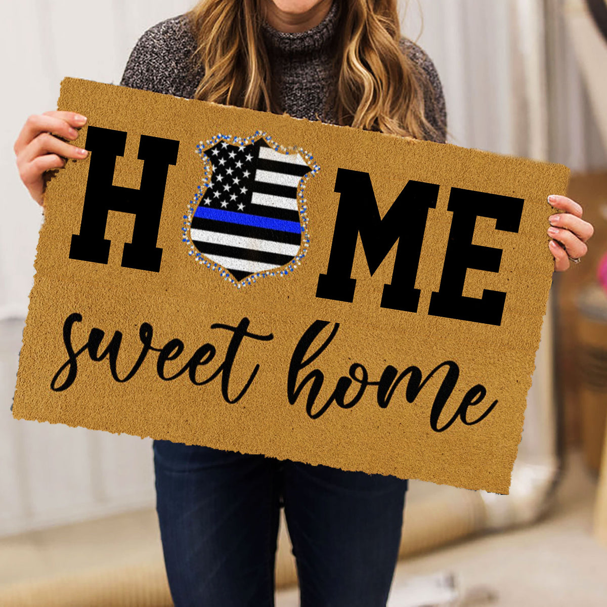 Person holding a tan police badge doormat with bold lettering and a welcoming script message