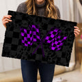 Person holding a racing-themed doormat with crossed purple checkered flags and black checkerboard design