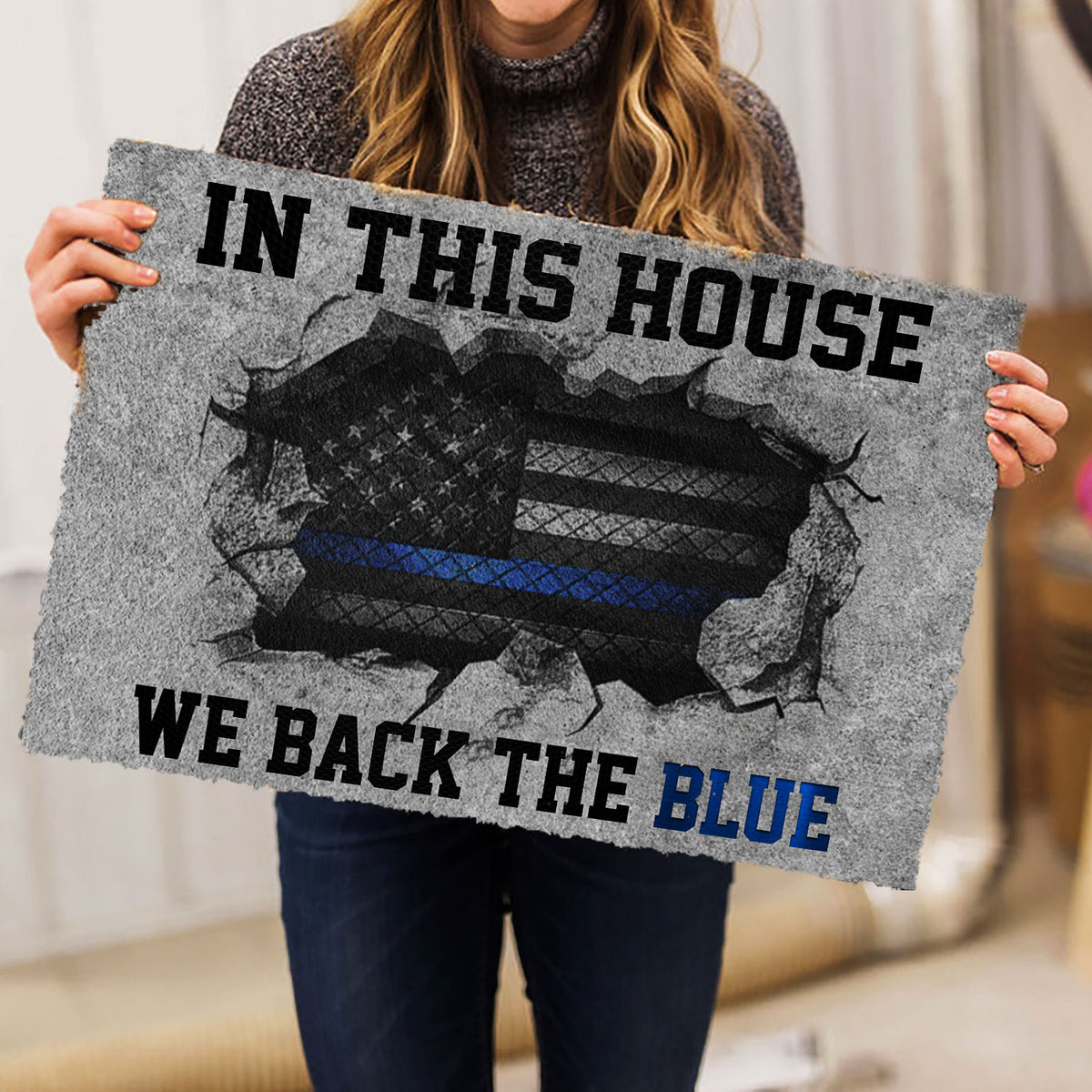 Police-themed doormat held indoors, featuring a blue line emblem and bold patriotic-style design
