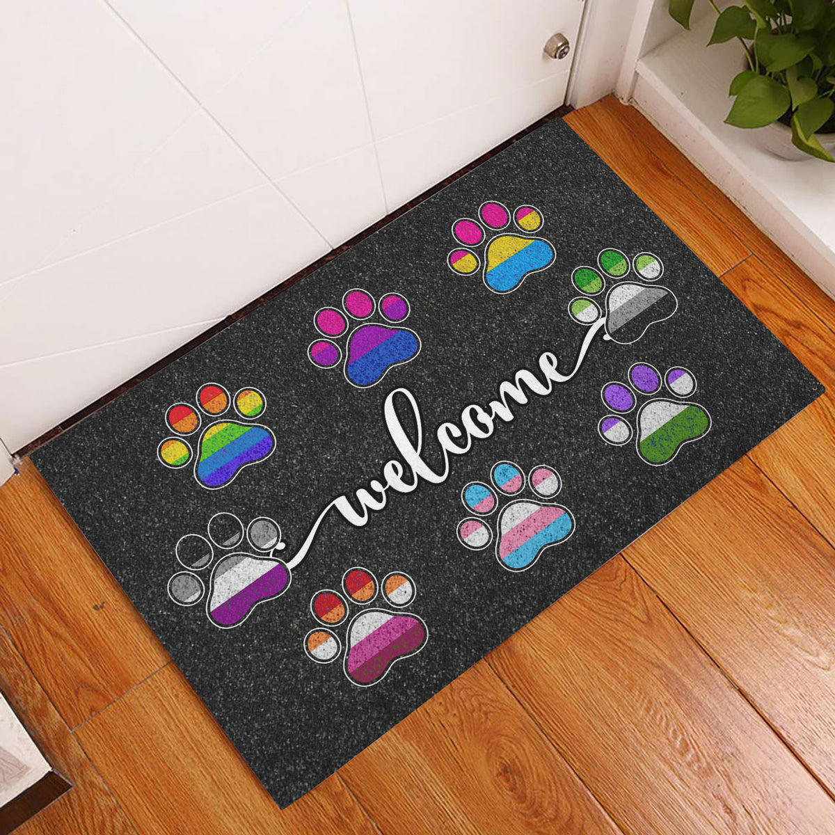 Pride-inspired paw print welcome mat displayed at an indoor entryway on a wood floor
