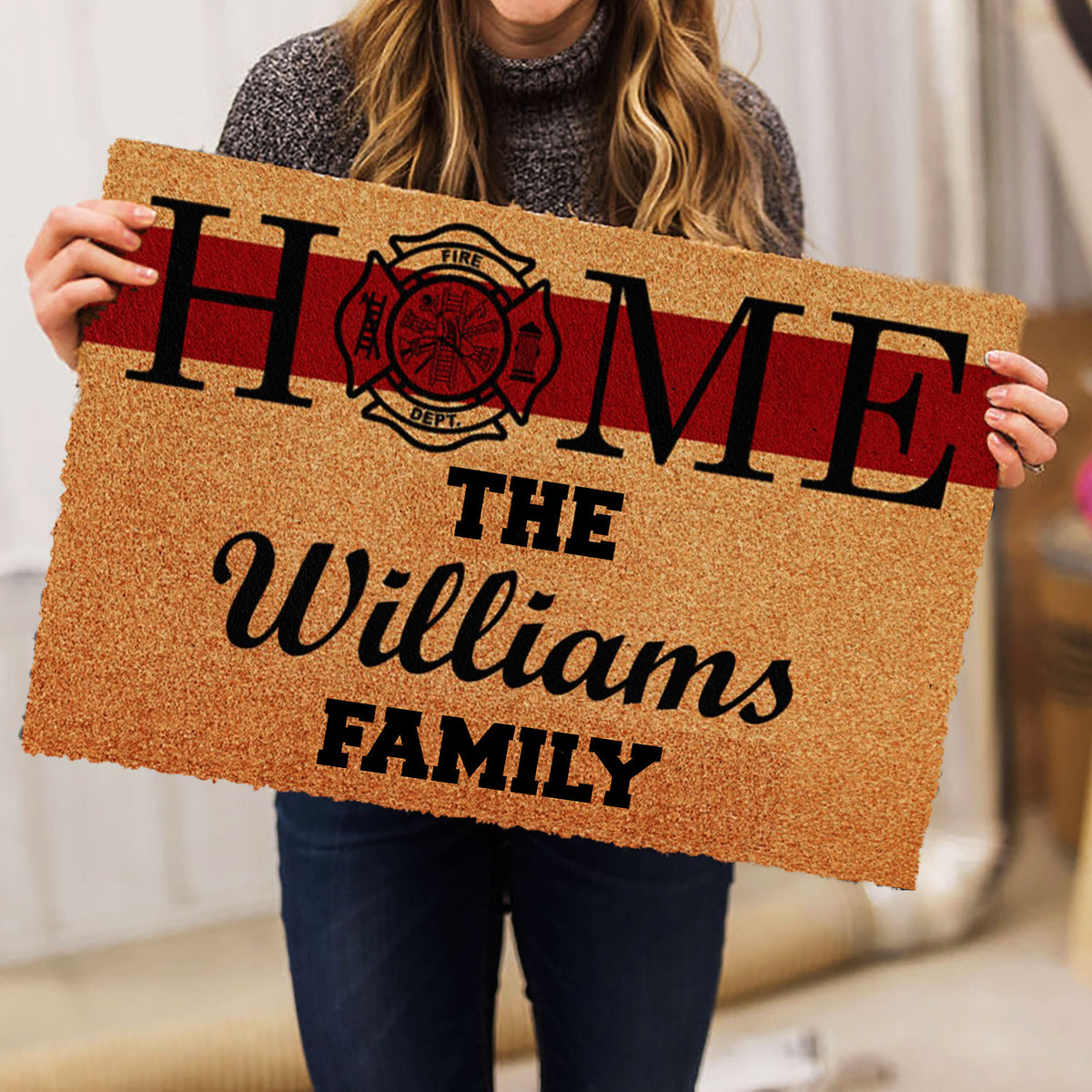 Person holding a firefighter family doormat featuring a red stripe and fire department emblem