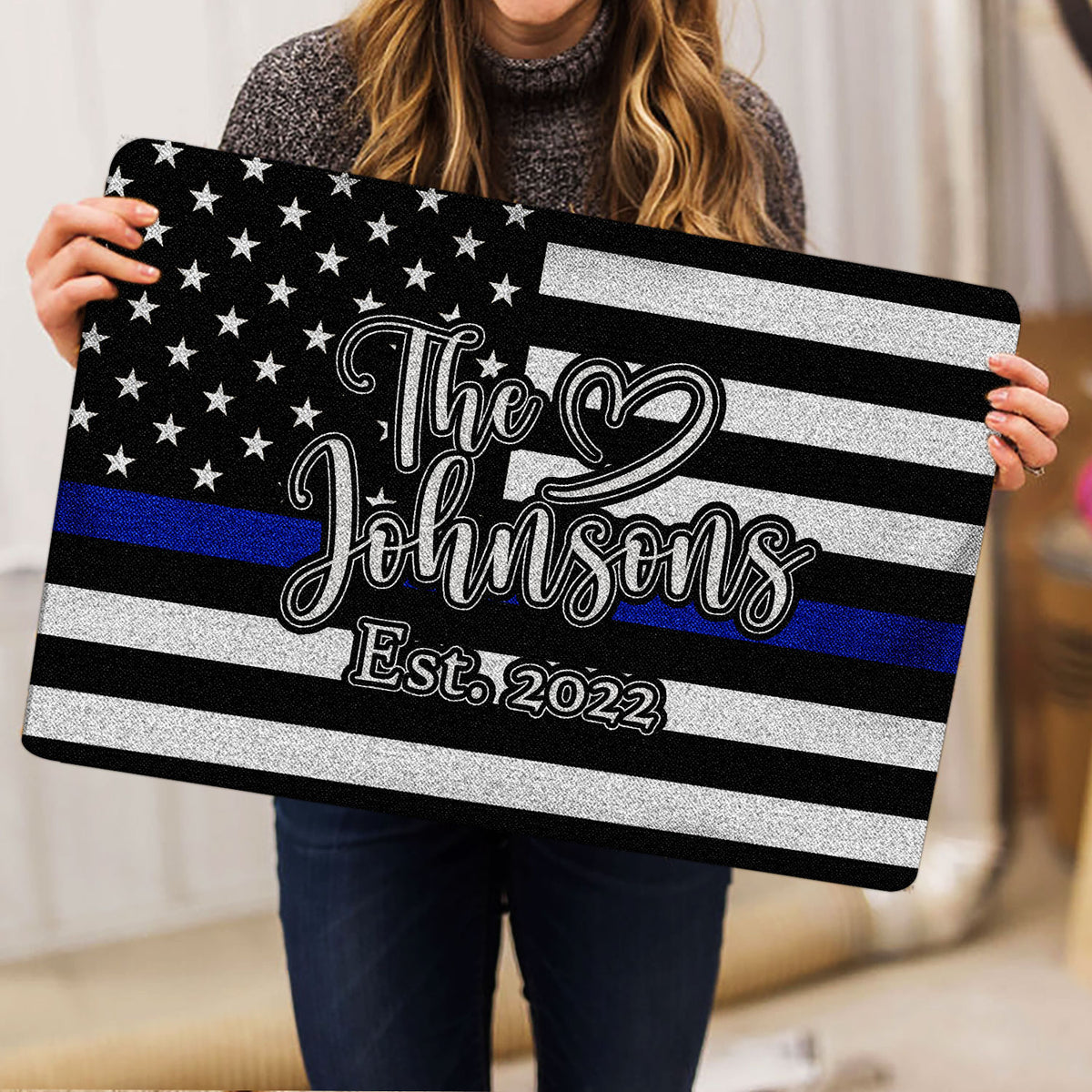 Person holding a police-support doormat featuring stars, stripes and a blue stripe