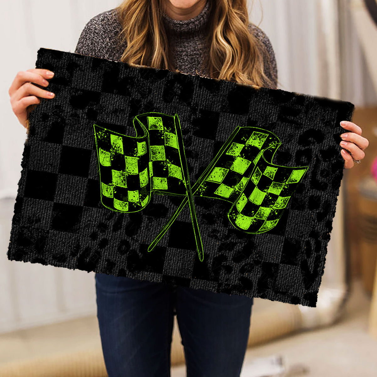 Person holding a black checkered racing doormat with bright green crossed flags