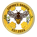Round custom bee garden metal sign featuring a honeybee, honeycomb, flowers, and a yellow border