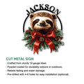 Decorative sloth metal sign shown with a wreath-inspired design, red holiday bow, evergreen sprigs, and pinecones