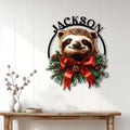 Christmas sloth wall decor displayed on a light wood-paneled wall above a console table