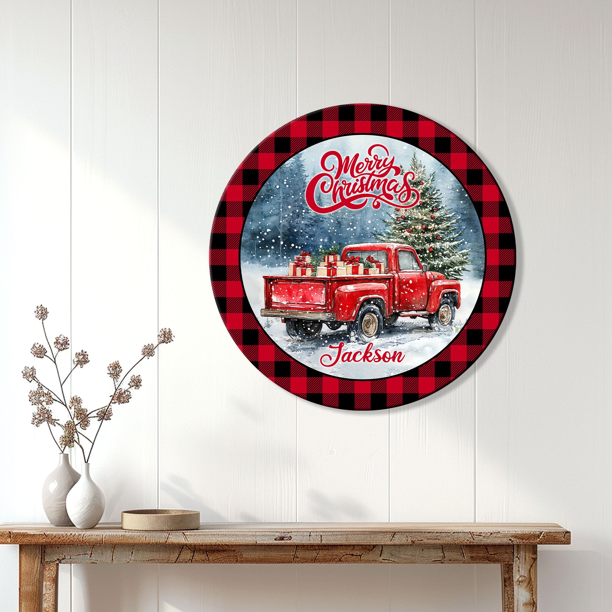 Round Christmas wall sign displayed above a console table with a red vintage truck and decorated tree