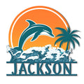 Dolphin metal sign featuring a leaping dolphin, ocean waves, palm tree, and circular sunset design