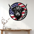 Patriotic Highland cow metal sign displayed on a white paneled wall above a rustic console table
