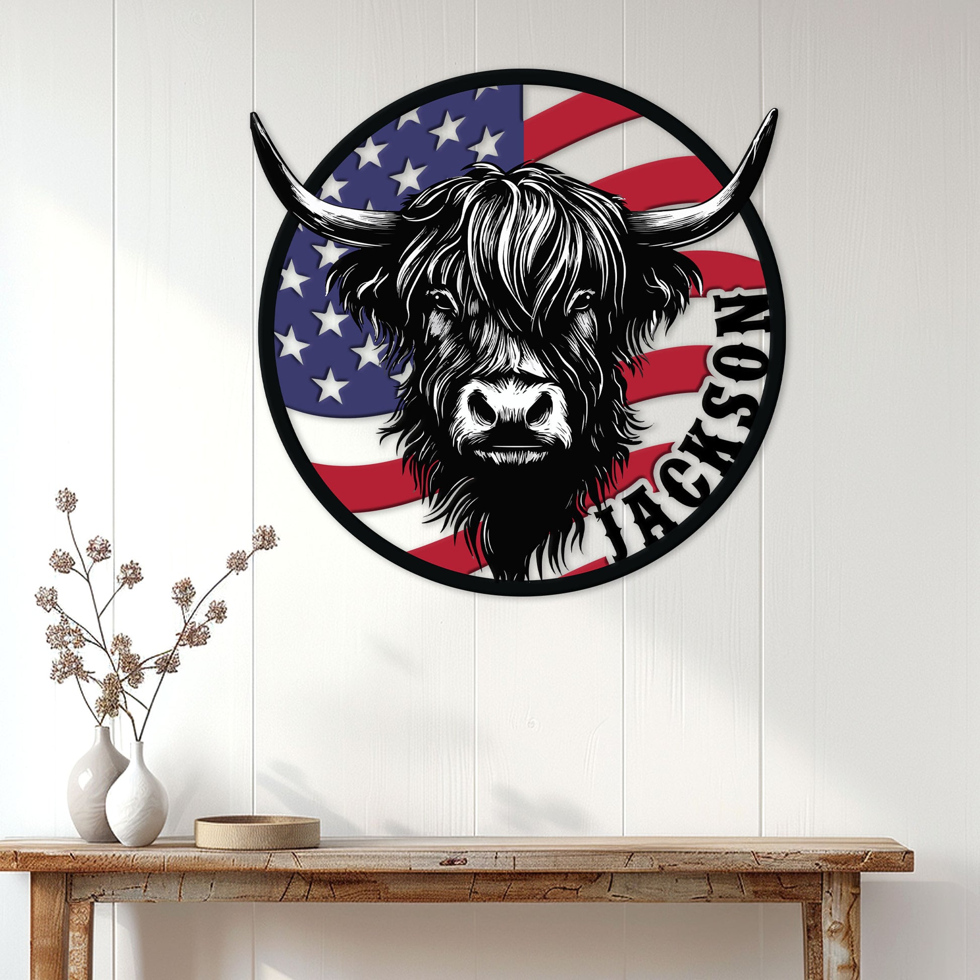 Patriotic Highland cow metal sign displayed on a white paneled wall above a rustic console table