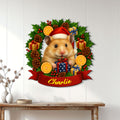 Christmas hamster metal sign displayed on a light wood-paneled wall above a console table