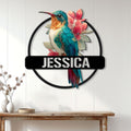 Floral hummingbird metal sign displayed on a light paneled wall above a wood console table