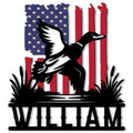 Patriotic duck hunting metal sign featuring a flying waterfowl silhouette over marsh grass and a flag design