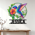 Colorful hummingbird wall sign displayed on a light paneled wall above a wood console table