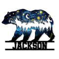 Bear-shaped metal sign with a starry night sky, crescent moon, mountain range, and forest landscape